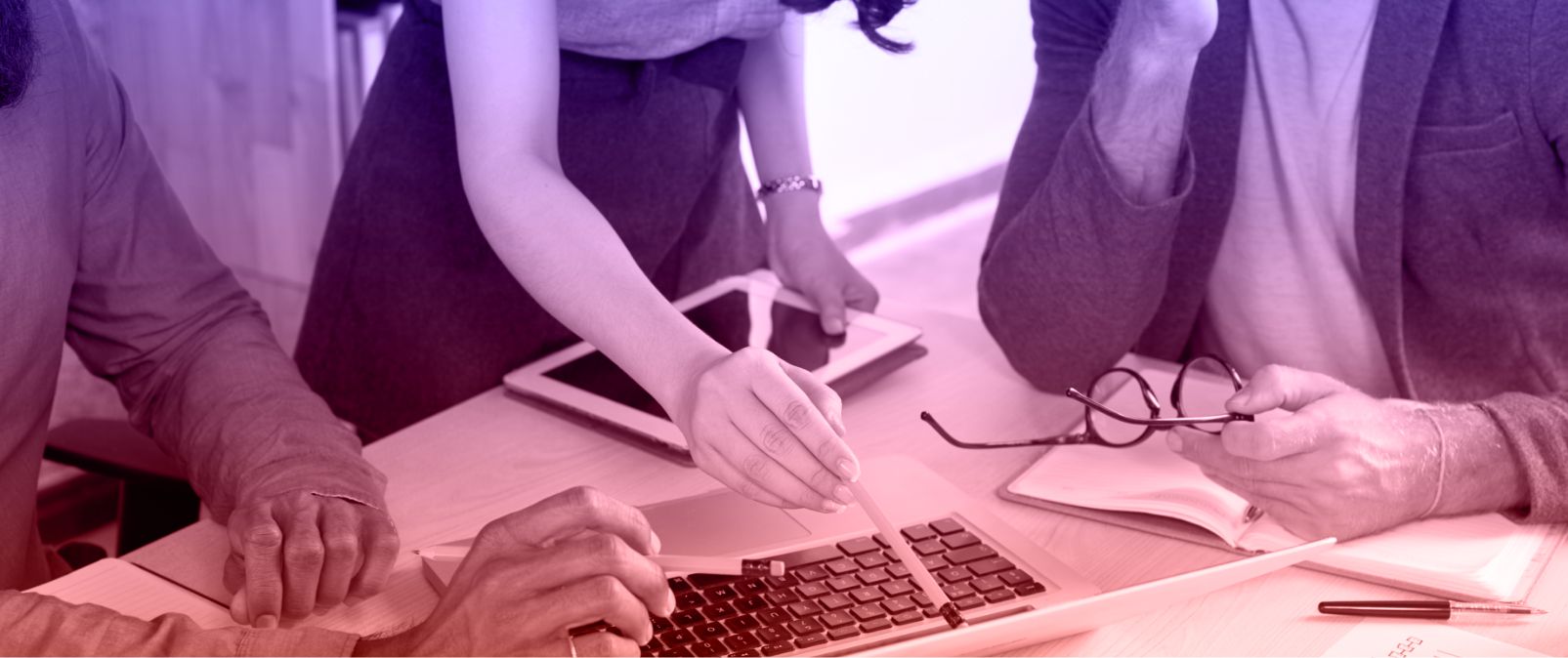 Three people collaborating on a laptop at a table, discussing how nonprofits can use impact narratives for data-driven results.