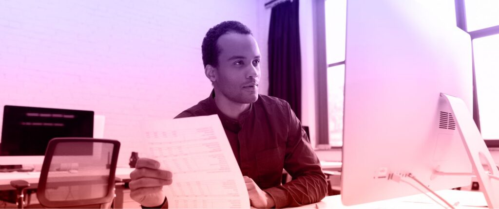 A man sits at a desk, focused on a piece of paper in front of him.